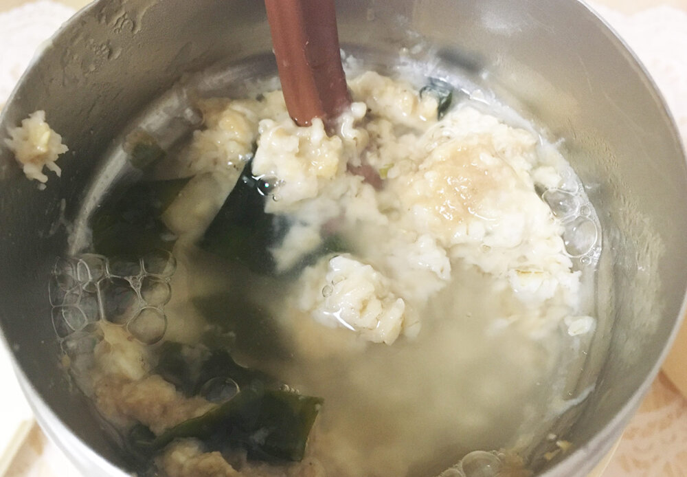 オートミールにスープの素とお湯を入れて混ぜている写真